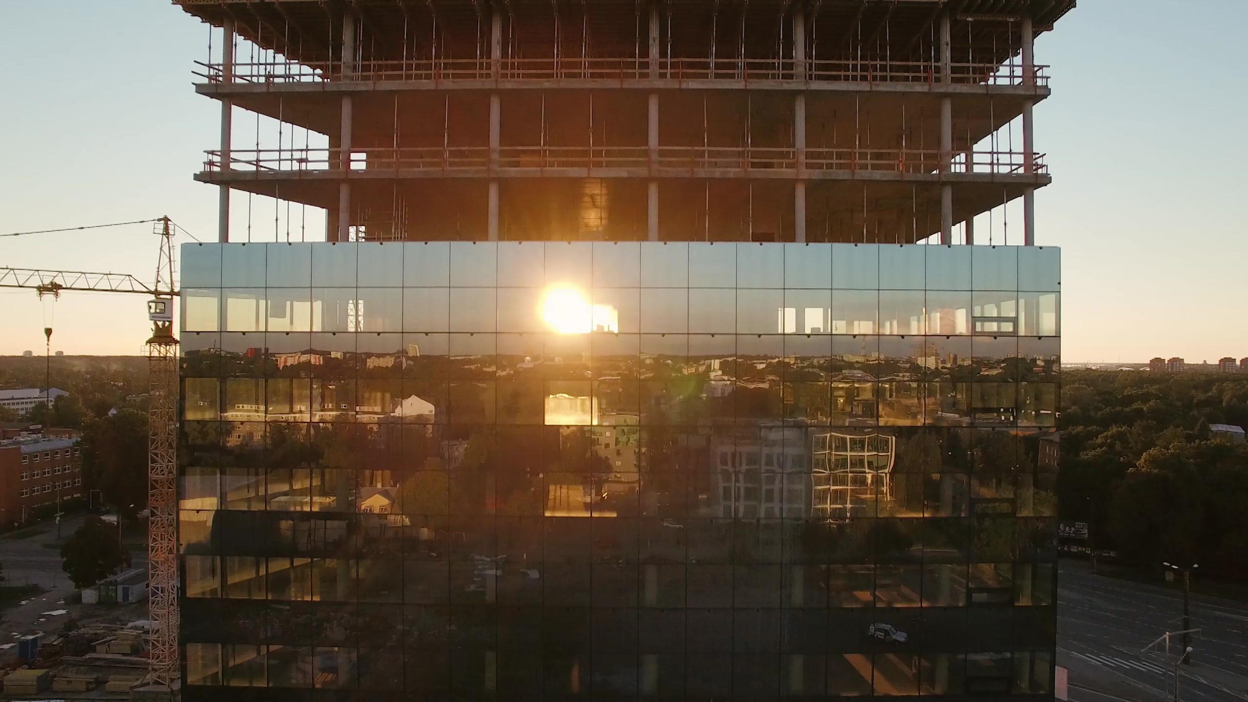 Aerial shot of an office building under construction, evening sun reflected in the glass facade