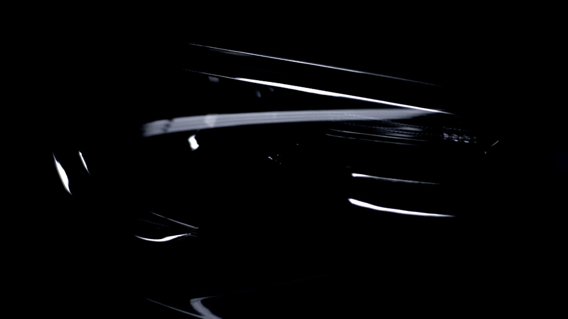 A vehicle detail shot at night, reflections running across the dark paint