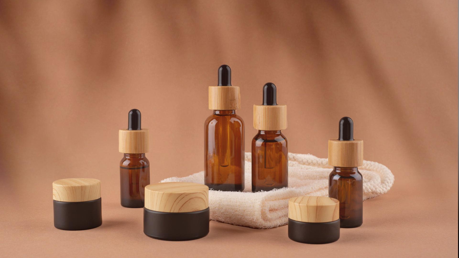 Cosmetic bottles and cream jars with wooden lids on a cloth in warm light